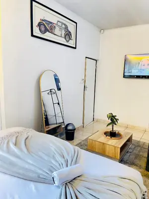 a bedroom with a bed and a table with a car on the wall at Genza Guesthouse in Pretoria in Pretoria