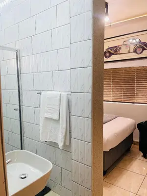 a bathroom with a sink and a bed and a tub at Genza Guesthouse in Pretoria in Pretoria