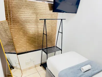 a room with a bed and a window with a blind at Genza Guesthouse in Pretoria in Pretoria