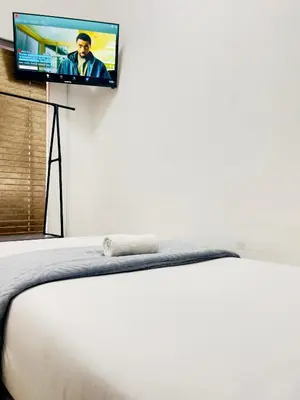 a bedroom with a bed with a flat screen tv on the wall at Genza Guesthouse in Pretoria in Pretoria