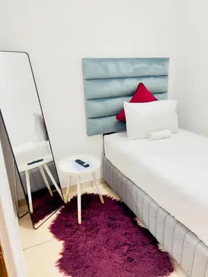 a bedroom with a bed and a mirror and a purple rug at Genza Guesthouse in Pretoria in Pretoria