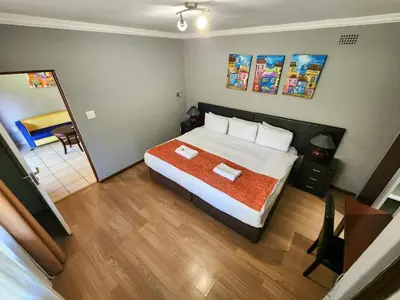 a bedroom with a large bed and a bathroom at The Venue Country Hotel & Spa in Hartbeespoort