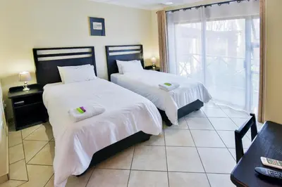 a bedroom with two beds with white sheets and a window at The Venue Country Hotel & Spa in Hartbeespoort