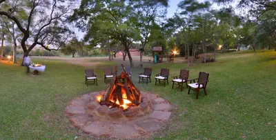 a fire pit in a park with chairs around it at The Venue Country Hotel & Spa in Hartbeespoort