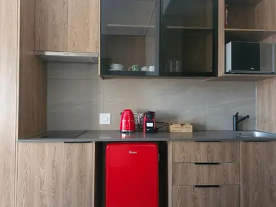 a kitchen with a red refrigerator and wooden cabinets at Emerald Studio Menlyn Maine in Pretoria