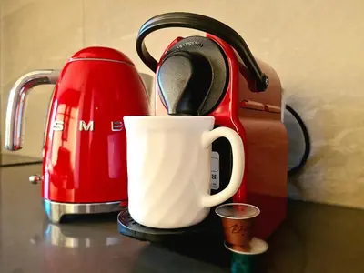 a red toaster and a coffee cup on a counter at Emerald Studio Menlyn Maine in Pretoria