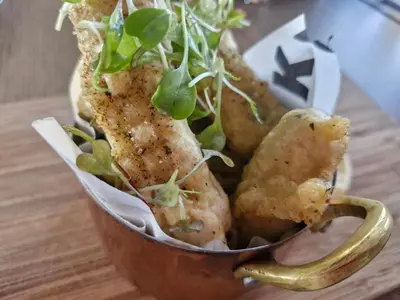 a cup filled with fried food on top of a table at Emerald Studio Menlyn Maine in Pretoria