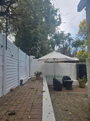 a patio with an umbrella and some chairs and an umbrella at Private Garden Studio near Menlyn in Pretoria