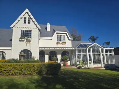 a large white house with a greenhouse in the yard at Private Garden Studio near Menlyn in Pretoria