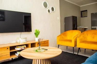 a living room with a table and two yellow chairs at Unit 235 at 50 On Lever in Midrand