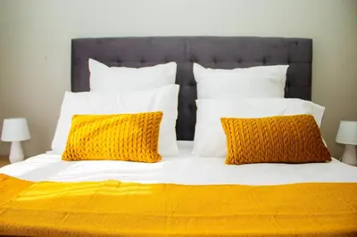 a bed with orange and white pillows on it at Unit 235 at 50 On Lever in Midrand
