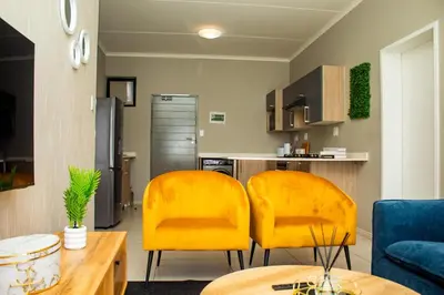 two yellow chairs in a living room with a kitchen at Unit 235 at 50 On Lever in Midrand