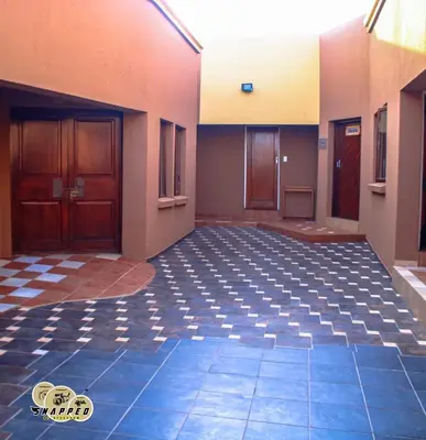 an empty room with a tile floor and two doors at EvehomeStay B&B in Soshanguve