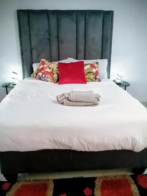 a large white bed with red pillows on it at GenAyah Hotel & Safari in Mtimba