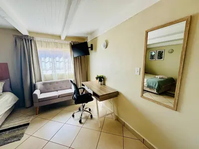 a bedroom with a desk and a mirror and a bed at The Well, Mokopane in Mokopane