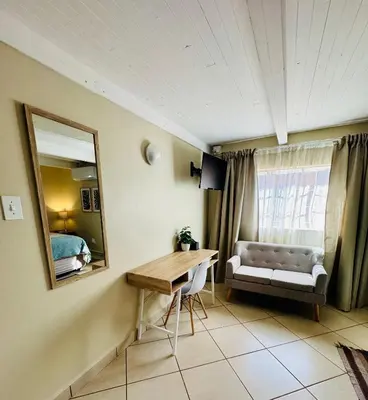 a room with a desk and a mirror and a bed at The Well, Mokopane in Mokopane