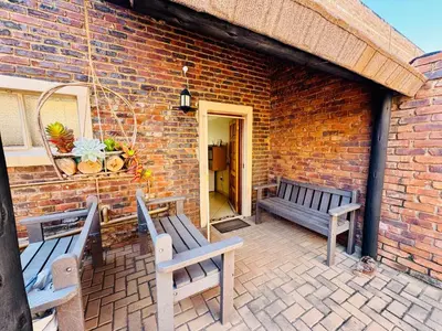 a patio with two benches and a brick wall at The Well, Mokopane in Mokopane