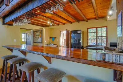 a large kitchen with a large wooden bar with stools at Bush Lodge Retreat Villa 29 in Warmbaths