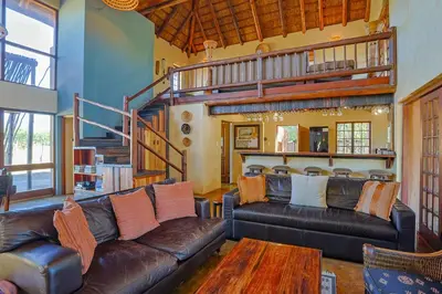 a living room with two leather couches and a wooden table at Bush Lodge Retreat Villa 29 in Warmbaths