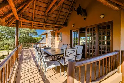 a wooden deck with a table and chairs on it at Bush Lodge Retreat Villa 29 in Warmbaths