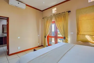 a bedroom with a large white bed and a window at Amani Lodge - Villa 81 in Warmbaths