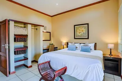 a bedroom with a large white bed and a red chair at Amani Lodge - Villa 81 in Warmbaths