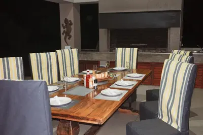 a wooden table and chairs with plates and napkins at Amani Lodge - Villa 81 in Warmbaths