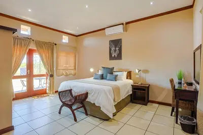 a bedroom with a bed and a table and a desk at Amani Lodge - Villa 81 in Warmbaths