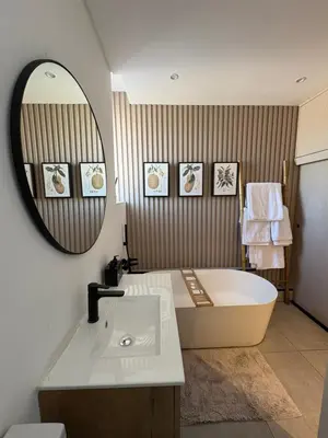 a bathroom with a tub and a sink and a mirror at Nare Penthouse in Pretoria