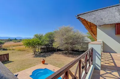 a house with a balcony with a blue pool at Stunning Bushveld Villa 84 in Warmbaths
