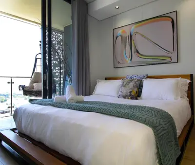 a large bed with a green blanket on top of it at 1Bed Stylish Apartment - Waterfall in Midrand
