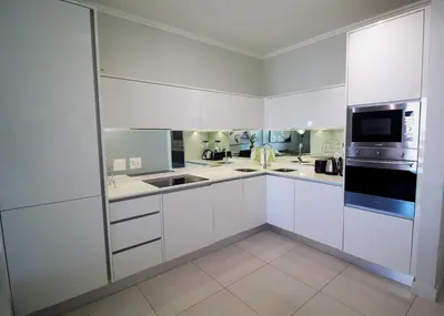 a white kitchen with a sink and a microwave at 1Bed Stylish Apartment - Waterfall in Midrand