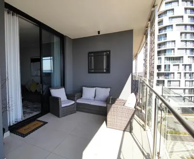 a balcony with a couch and chair on a building at 1Bed Stylish Apartment - Waterfall in Midrand