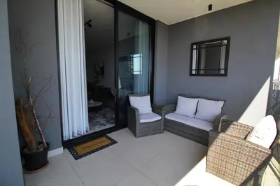 a balcony with two chairs and a window at 1Bed Stylish Apartment - Waterfall in Midrand