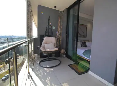 a balcony with a chair and a bed in a room at 1Bed Stylish Apartment - Waterfall in Midrand