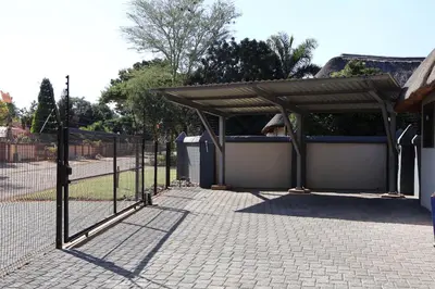 a fence with a wooden canopy next to a driveway at Golden Casa in Mokopane