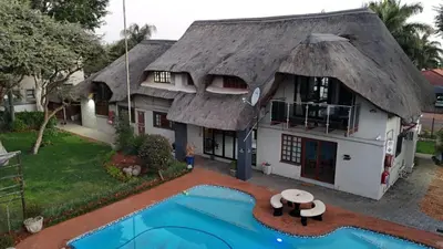 a house with a thatched roof and a swimming pool at Golden Casa in Mokopane