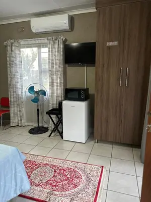 a bedroom with a room with a fan and a window at Nkandla Yethu Guest House in Nelspruit
