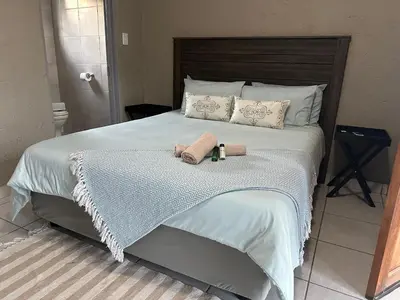 a bedroom with a bed with two towels on it at Nkandla Yethu Guest House in Nelspruit