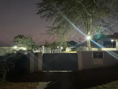 a fence and a tree at night with lights at Nkandla Yethu Guest House in Nelspruit