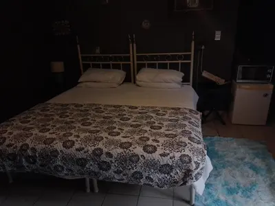 a bedroom with a bed with a brown and white comforter at Aloha Menlyn Lodge in Pretoria
