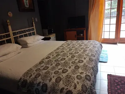 a bedroom with a large bed with a flowered blanket at Aloha Menlyn Lodge in Pretoria