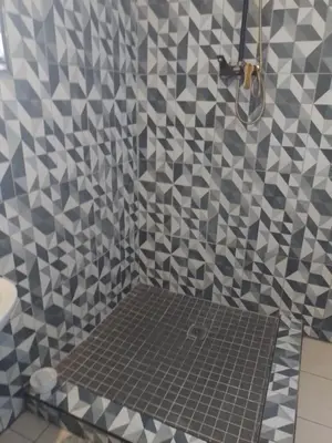 a bathroom with a shower with a tile wall at Aloha Menlyn Lodge in Pretoria