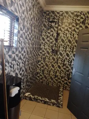 a bathroom with a shower with a bench on the wall at Aloha Menlyn Lodge in Pretoria