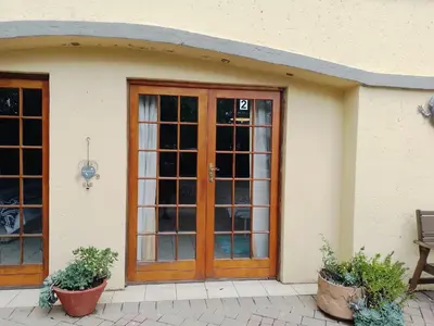 a front door of a house with two potted plants at Aloha Menlyn Lodge in Pretoria
