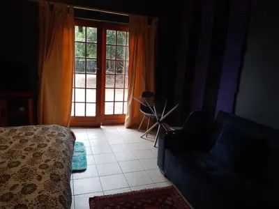 a living room with a couch and a sliding glass door at Aloha Menlyn Lodge in Pretoria