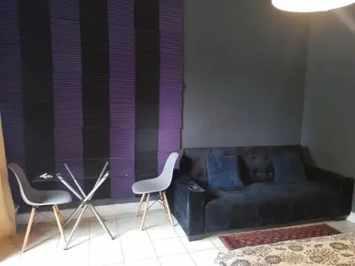 a living room with a black couch and two chairs at Aloha Menlyn Lodge in Pretoria