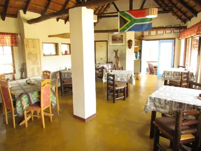 a dining room with tables and chairs and a pole at Thokozani Lodge in White River