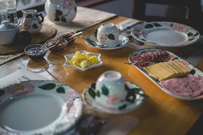 a wooden table with plates and cups and dishes on it at Thokozani Lodge in White River