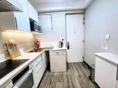 a small kitchen with white appliances and wooden floors at Luxurious Loft in Pretoria